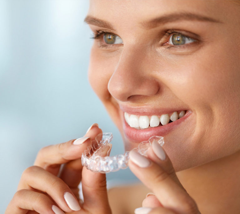 a lady is putting invisalign and smiling
